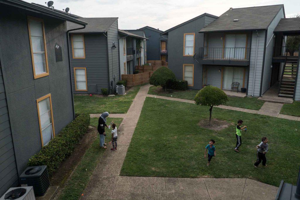 A refugee family playing in the courtyard of their apartment complex. IRC/AOberstadt